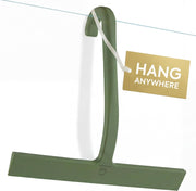 Green silicone shower squeegee with J-shaped hook hanging on a glass shower door